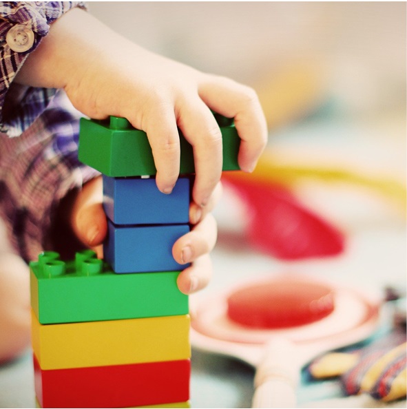 Kinderhände bauen mit Plastikbausteinen